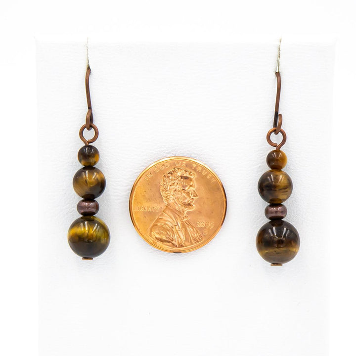 Earth Song Jewelry handmade Tigereye Copper earrings. Next to a coin for sizing context.