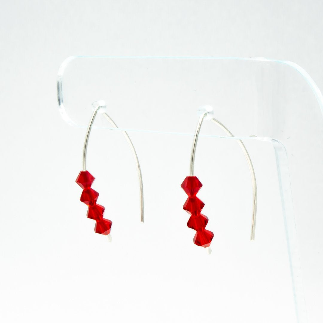 Earth Song Jewelry handmade Sparkling Ruby Red Silver Earrings. Made with tarnish resistant Argentium sterling silver. Displayed on a stand for an angle view. 